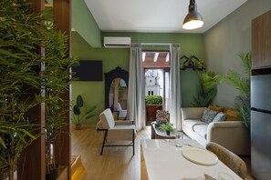 A living room with a sofa, a dining table, and a kitchen area with a refrigerator. - Loft moderno para 2 personas | Plaza Bolívar, Casco Viejo. (Casco Viejo)