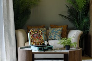 Un salon chaleureux avec un canapé, un tableau coloré et une plante en pot.