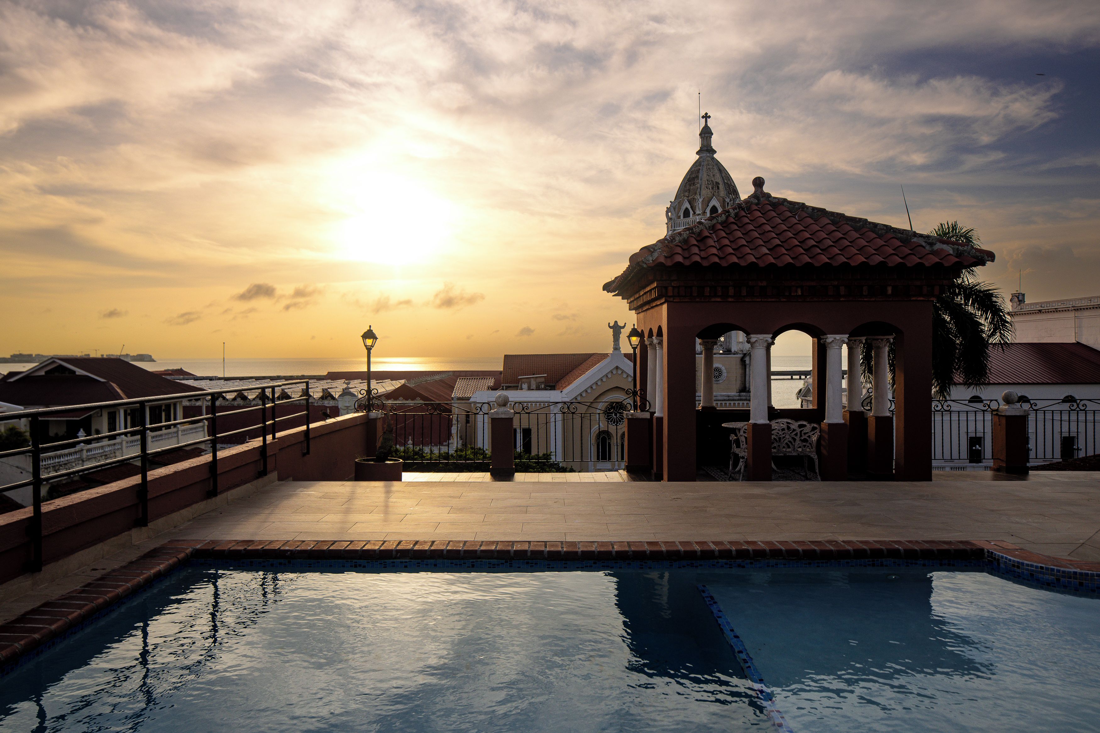 Una piscina con vistas a la puesta de sol, un pabellón y un puente.