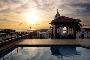A swimming pool with a view of the sunset, a gazebo, and a bridge. - Loft moderno para 2 personas | Plaza Bolívar, Casco Viejo. (Casco Viejo)
