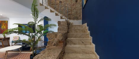 A staircase with stone steps leading to a room with a blue wall and a stone wall.