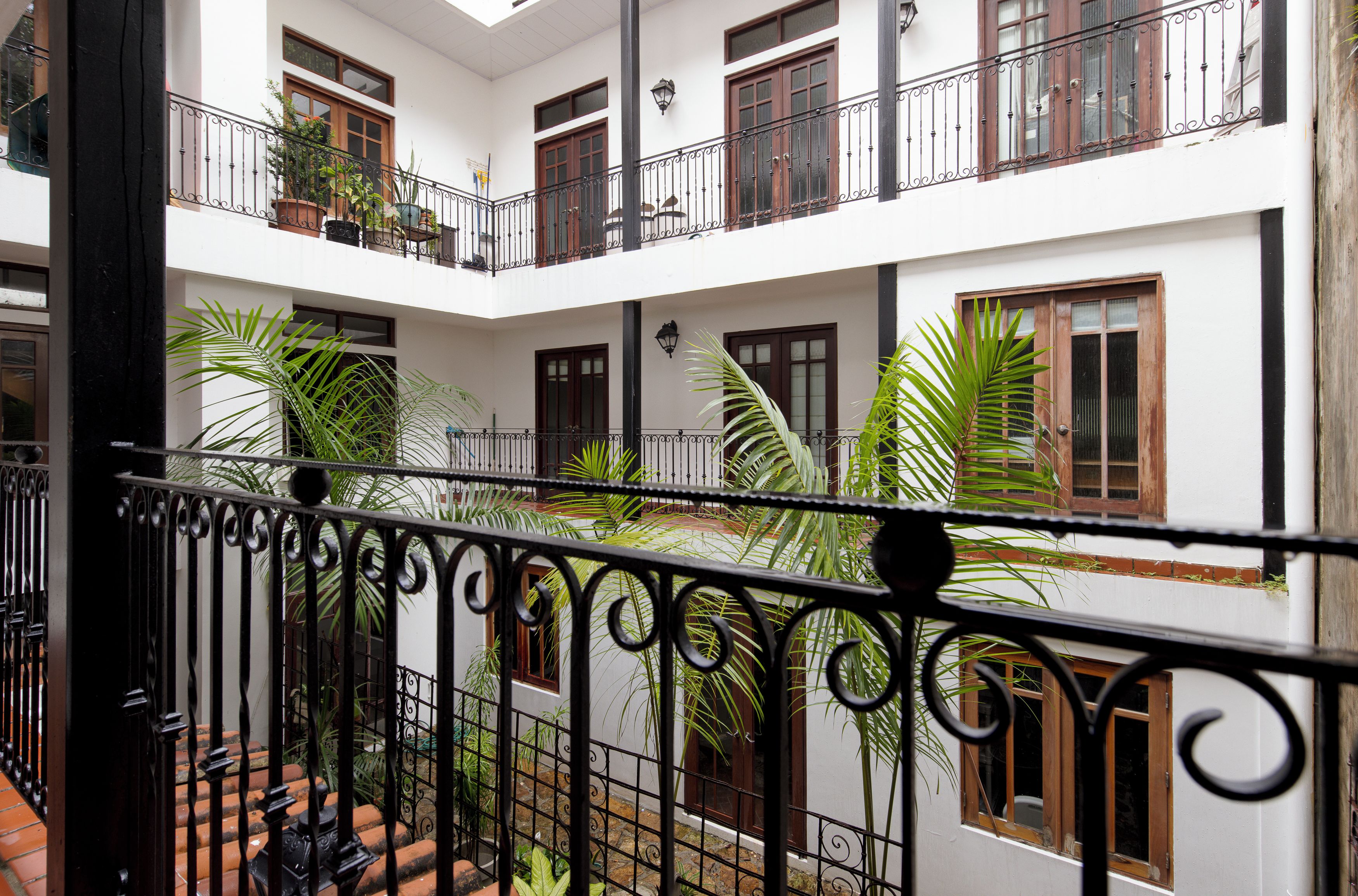 A multi-level courtyard with balconies, potted plants, and a tiled floor.