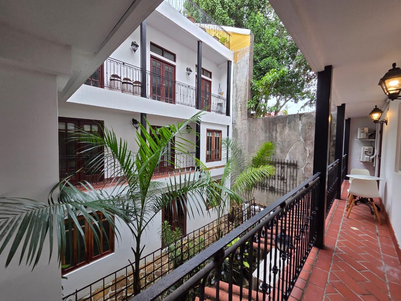 A balcony with a tiled floor, a railing, and potted plants.