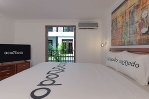 A hotel room with a bed, a television, a painting, and a view of the outside. - 2 Hab. + 1.5 Baños | Dúplex de dos niveles con balcón | Casco Viejo | Estadías de 30+ noches (Casco Viejo)