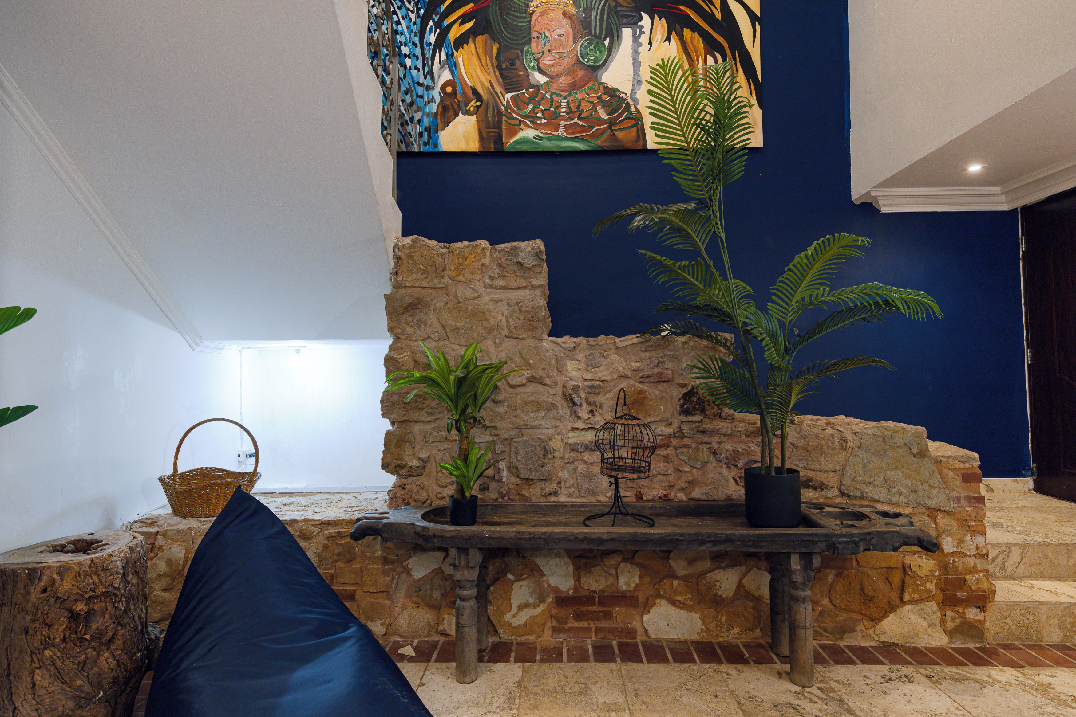 A room with a stone wall, a wooden bench, and a potted plant.