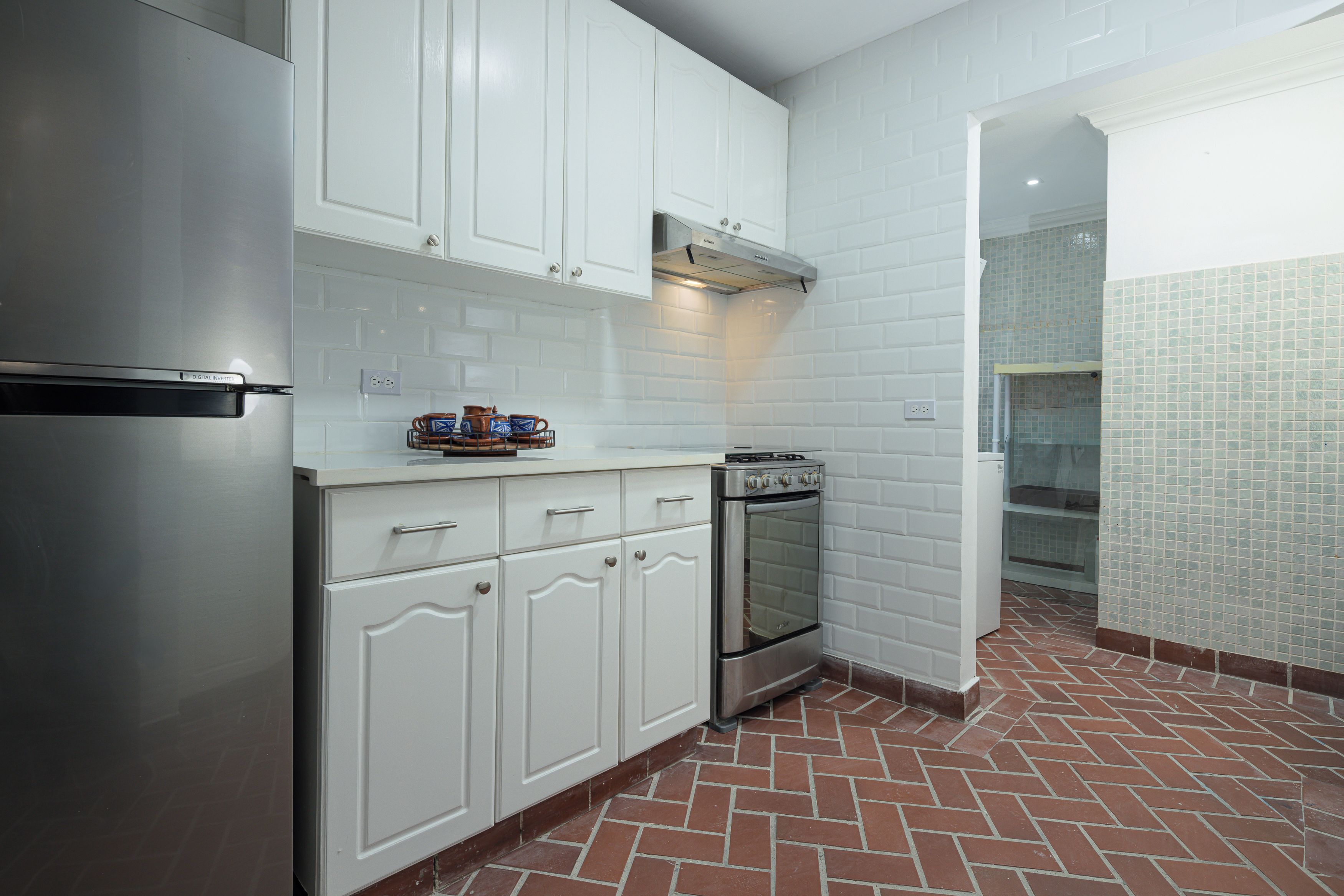 A kitchen with white cabinets, a stainless steel refrigerator, a built-in oven, and a tiled backsplash.