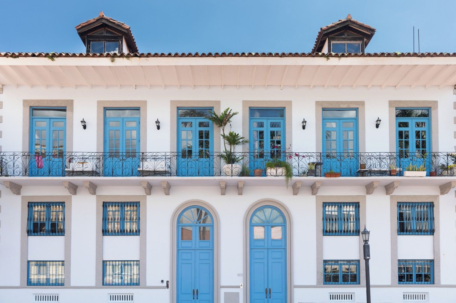 A building with multiple balconies, blue doors, and windows with metal grilles.