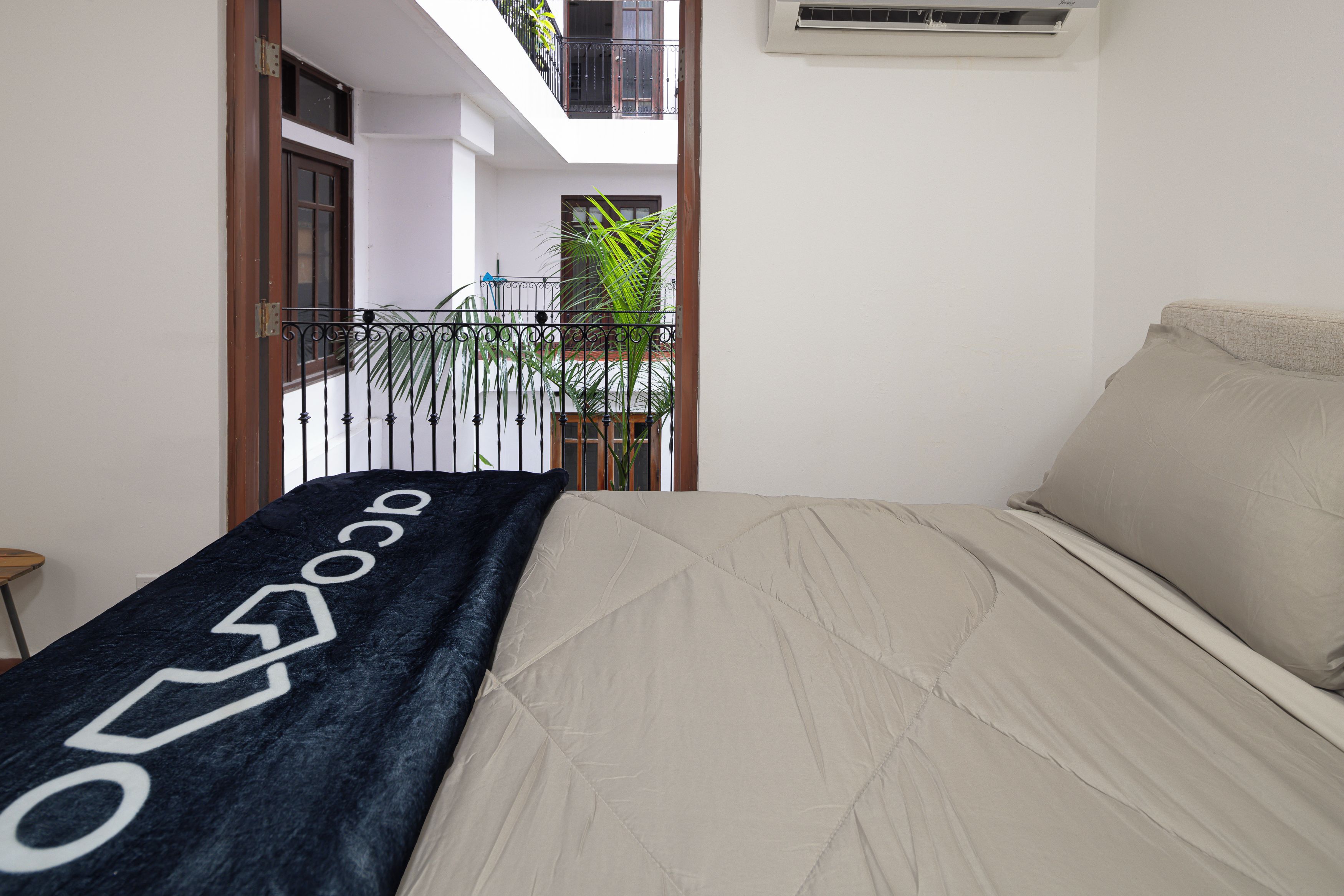 A bedroom with a bed, a window, and a balcony.