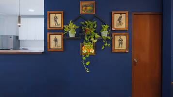 A room with a blue wall, a wooden door, and a kitchen area with a white cabinet and a hanging light fixture.
