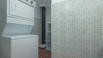 A compact kitchen with a built-in washer and dryer, a tiled backsplash, and a brick-patterned floor.