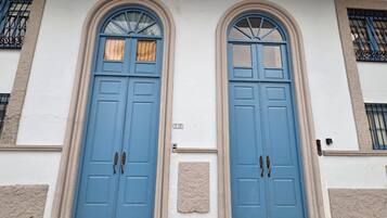 A building with two blue doors, a small plaque, and a window with a barred design.