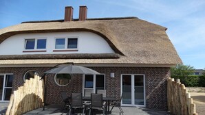 A house with a thatched roof, brick exterior, and a patio with outdoor furniture. - Farm in Dahme with sauna and Wi-Fi (Dahme)