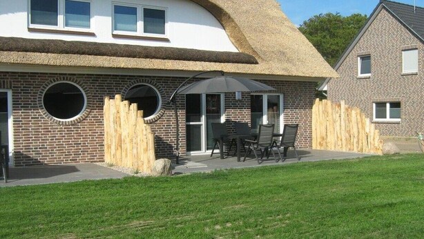 A house with a thatched roof, brick walls, and a patio with outdoor furniture. - Farm in Dahme with sauna and Wi-Fi (Dahme)