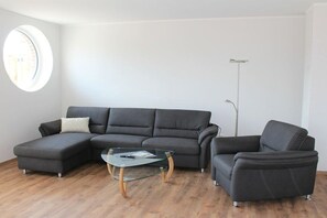 A modern living room with a sectional sofa, a glass coffee table, and a floor lamp.
