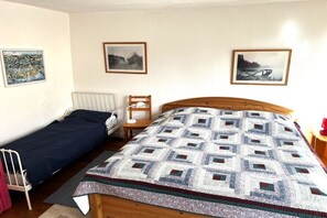 A room with a single bed, a bedside table, a chair, and a radiator. There are three framed pictures on the wall. - Holiday apartment with 1 bedroom (Schönberg)