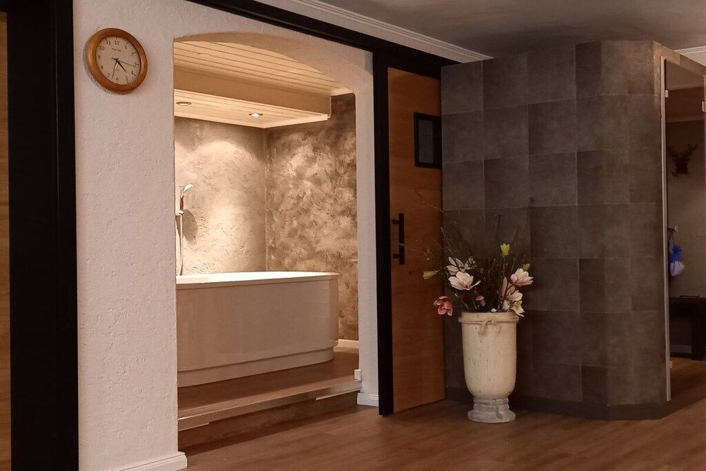 A bathroom with a freestanding bathtub, a wooden vanity, and a large potted plant.