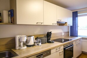 Eine moderne Küche mit weißen Schränken, einem eingebauten Backofen, einer Kaffeemaschine, einem Toaster und einem Wasserkocher.