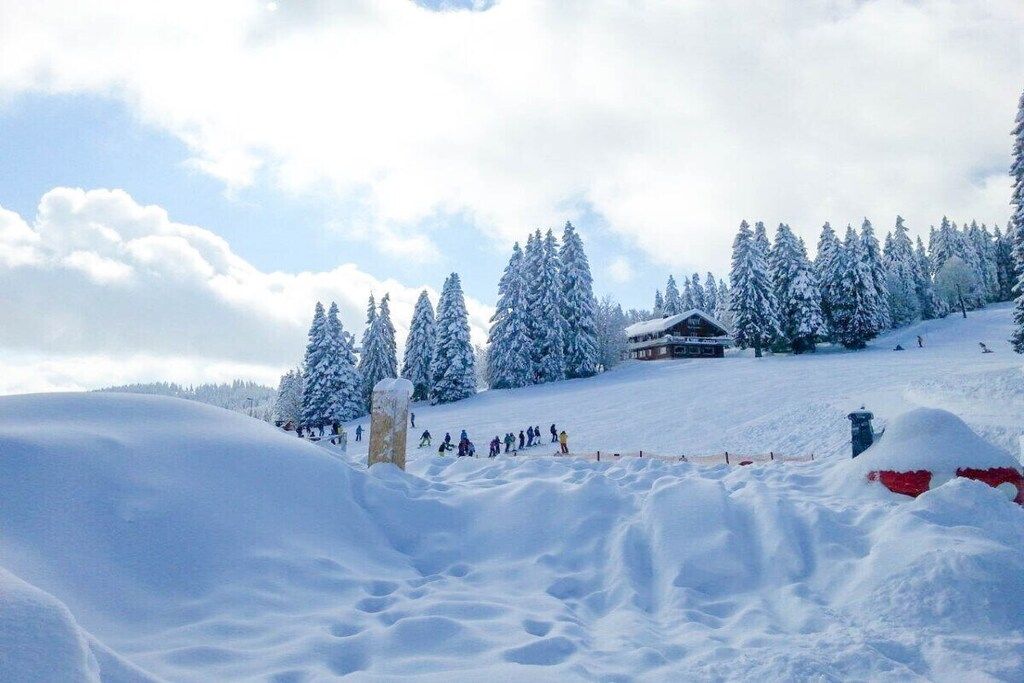 A snowy landscape with a ski resort, including a lodge and ski slopes.