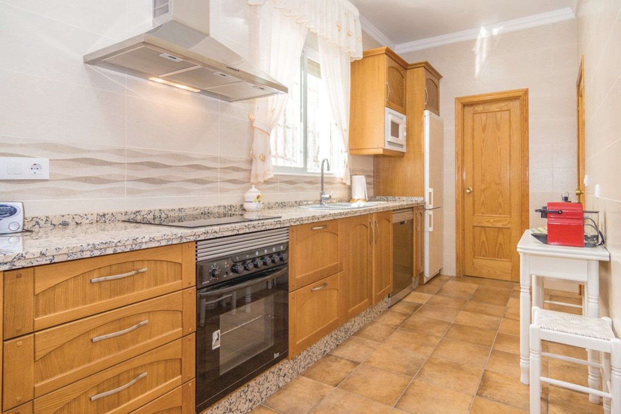 A kitchen with wooden cabinets, a built-in oven, a microwave, and a sink.