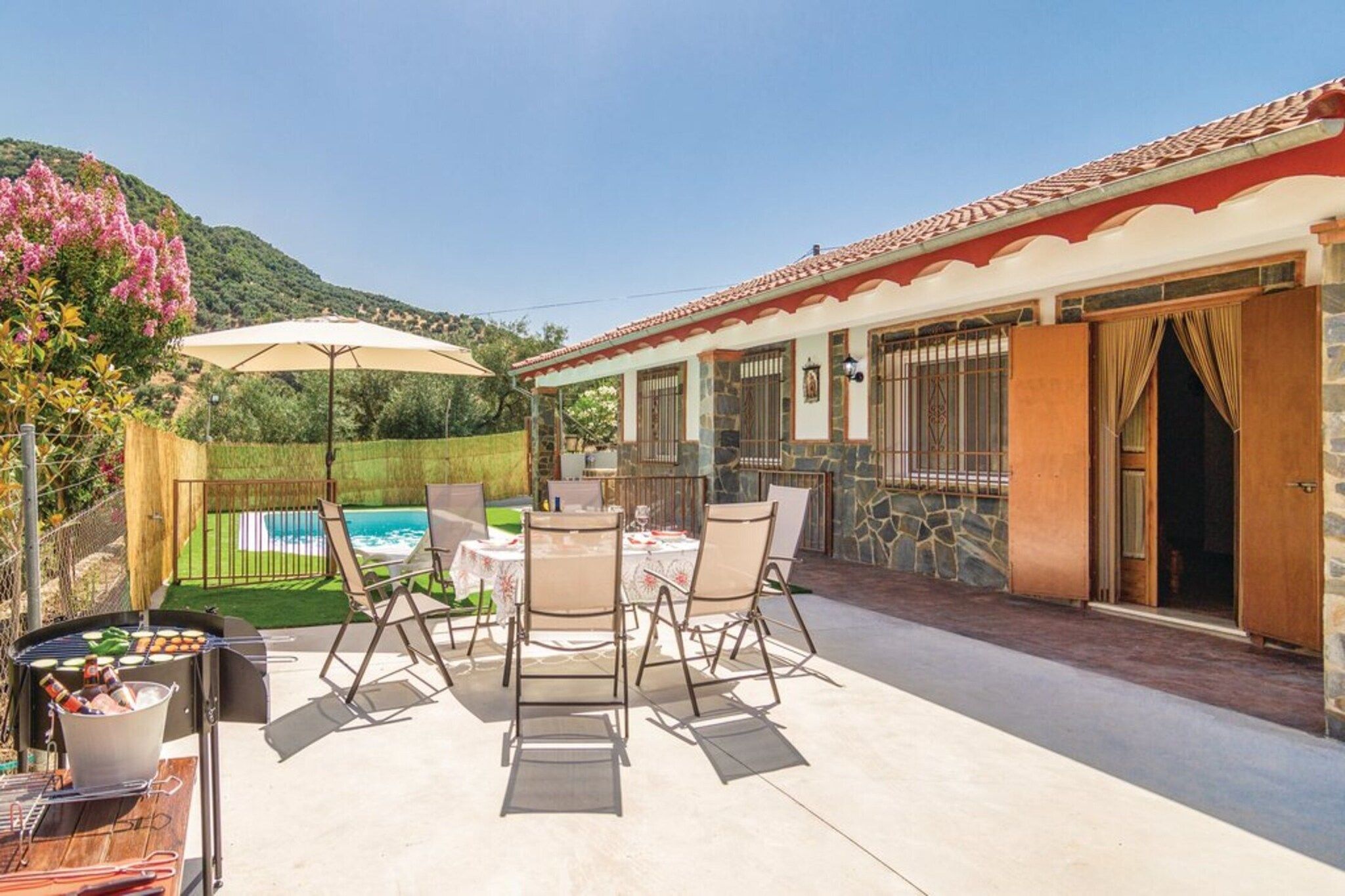 Eine Terrasse mit Pool, Sitzgelegenheiten im Freien und einem Gebäude mit steinernen Mauern und einem Ziegeldach.