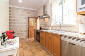 Eine Küche mit Holzschränken, einem Edelstahl-Geschirrspüler und einer Arbeitsplatte aus Granit.