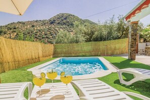 Una piscina con el paisaje de montañas al fondo, rodeada de césped y una valla de madera.