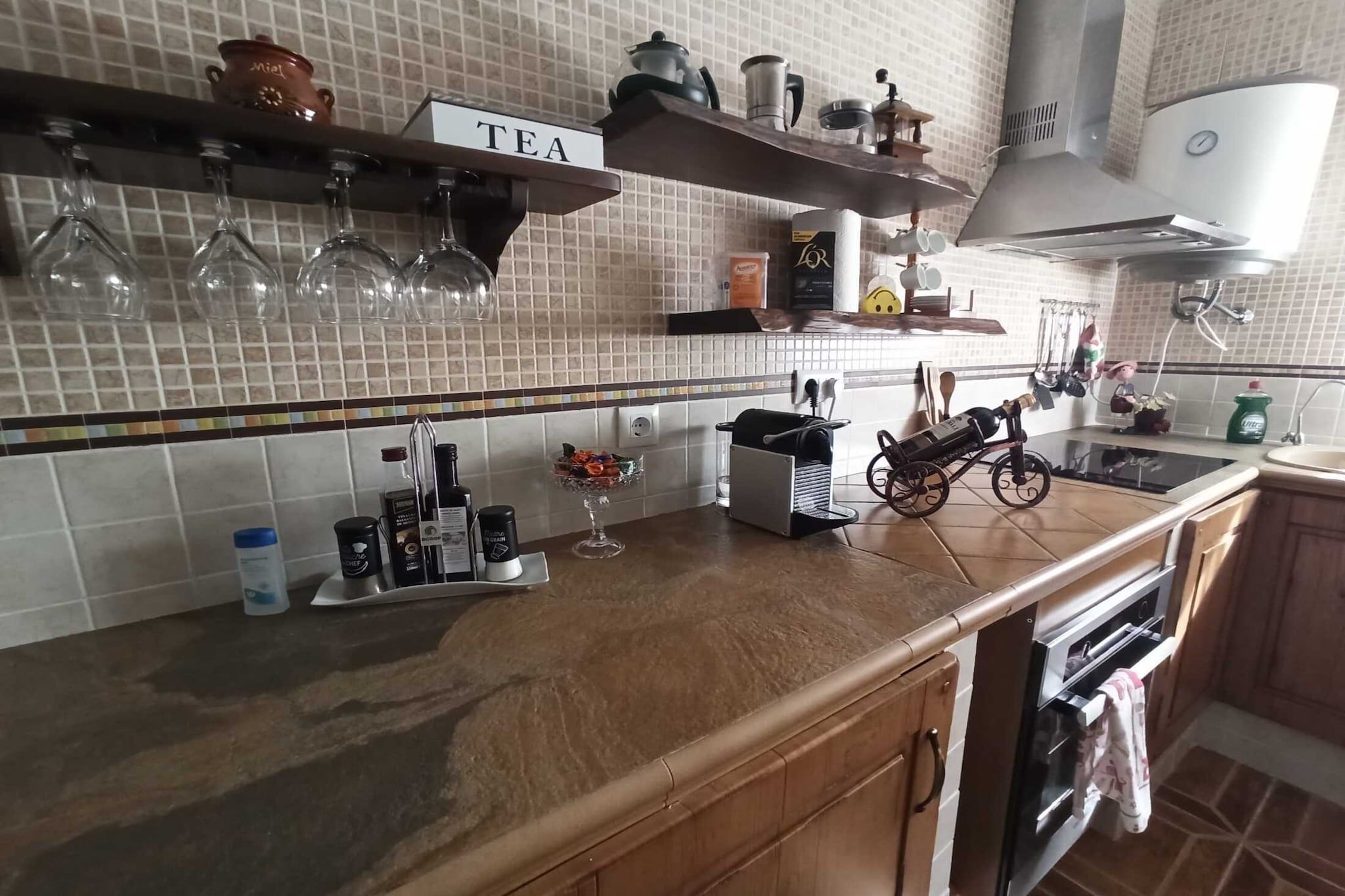 Ett kök med en bänkskiva, en hylla för te och en kaffemaskin.