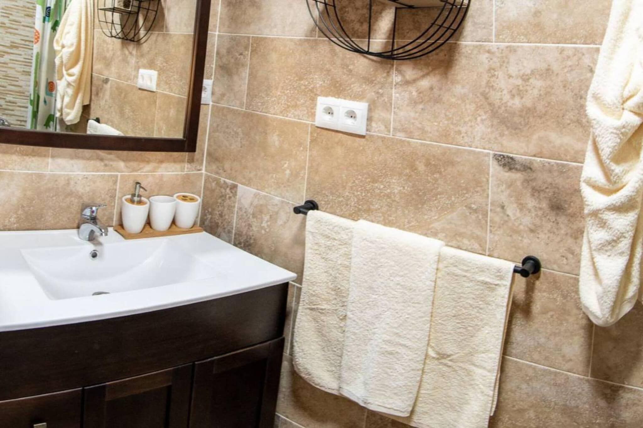 A bathroom with a sink, mirror, towel rack, and a towel.