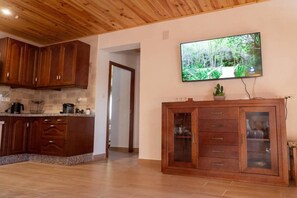 Eine Küche mit Holzschränken, einer Arbeitsplatte und einem an der Wand befestigten Fernseher.