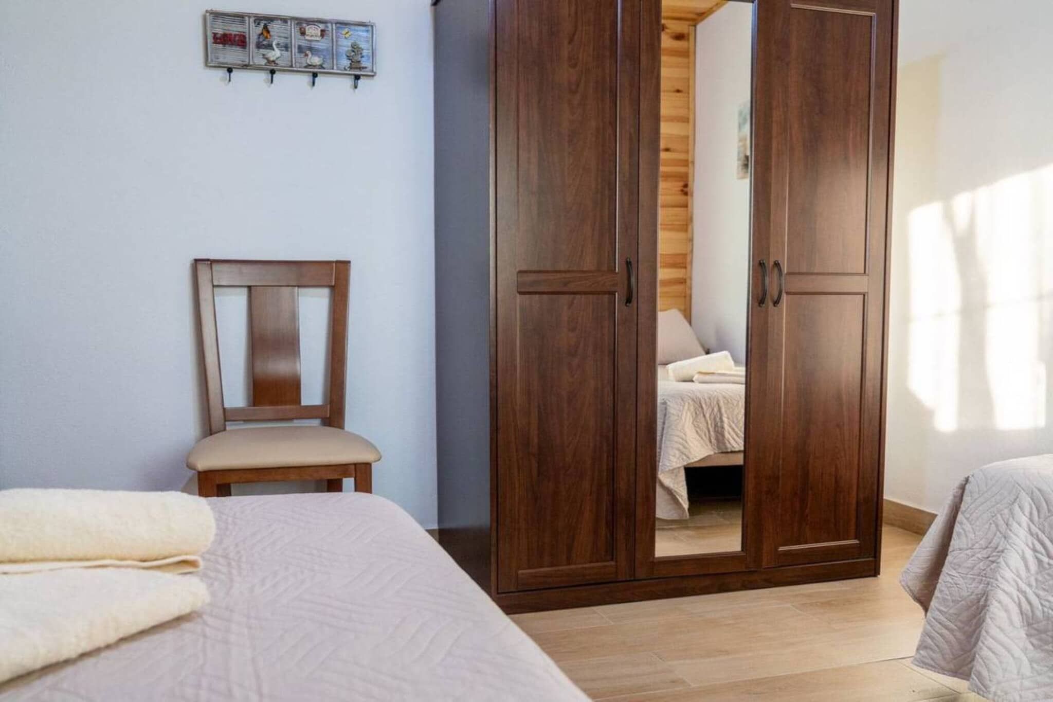 A bedroom with a bed, a chair, and a wardrobe.