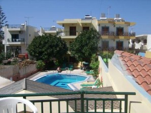Un edificio residencial con piscina, balcones y cielo despejado.