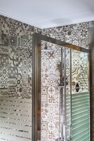 Un baño con baldosas estampadas, zona de ducha y puerta de cristal.