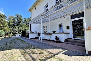 A two-story building with a covered porch, potted plants, and a bench. - Fiedler holiday apartments (Heringsdorf (Seebad))