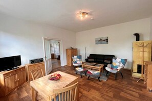 A living room with a television, wooden furniture, a sofa, and a fireplace. - Fiedler holiday apartments (Heringsdorf (Seebad))
