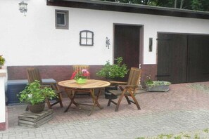 An outdoor patio with a round wooden table and four chairs, surrounded by potted plants. - Fiedler holiday apartments (Heringsdorf (Seebad))