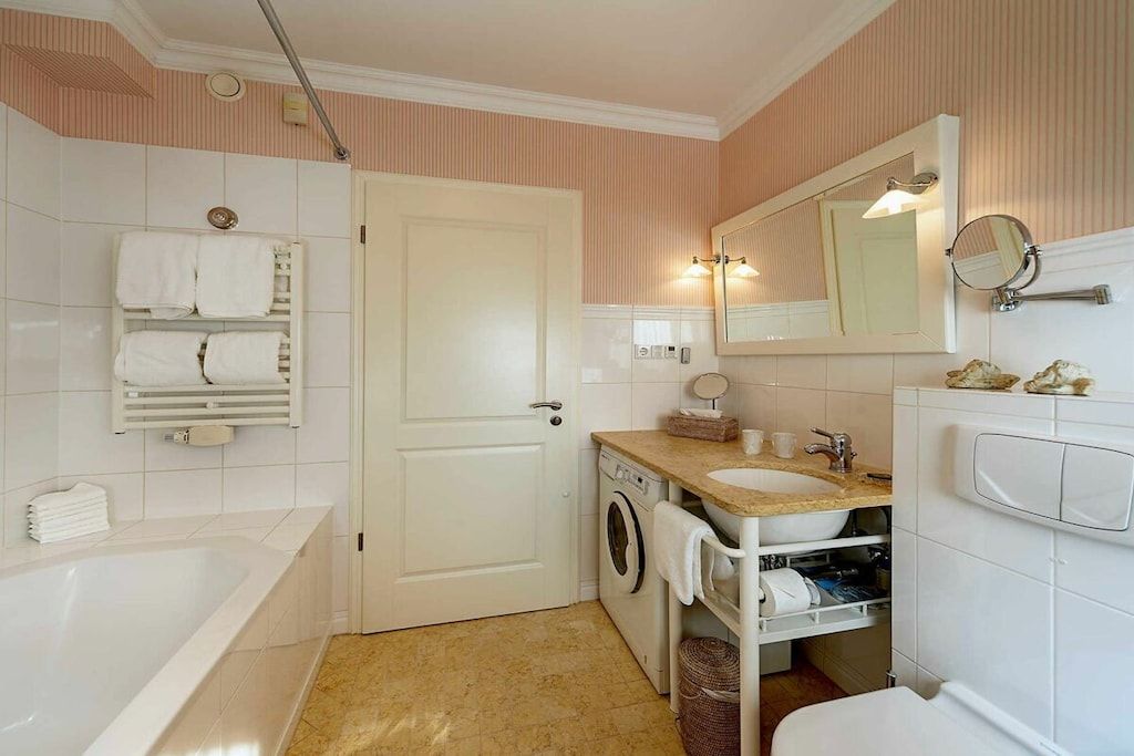 Ein Badezimmer mit Badewanne, Waschmaschine, Waschbecken und Toilette.