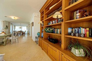 A spacious living area with a wooden bookshelf, a dining table, and chairs. - 4 „Ut de Franzosentid (Kühlungsborn)