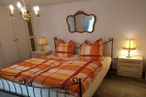 A bedroom with a bed, a nightstand, a lamp, a mirror, and a chandelier. - Hex"nhäusla in Aufseß (Aufseß)