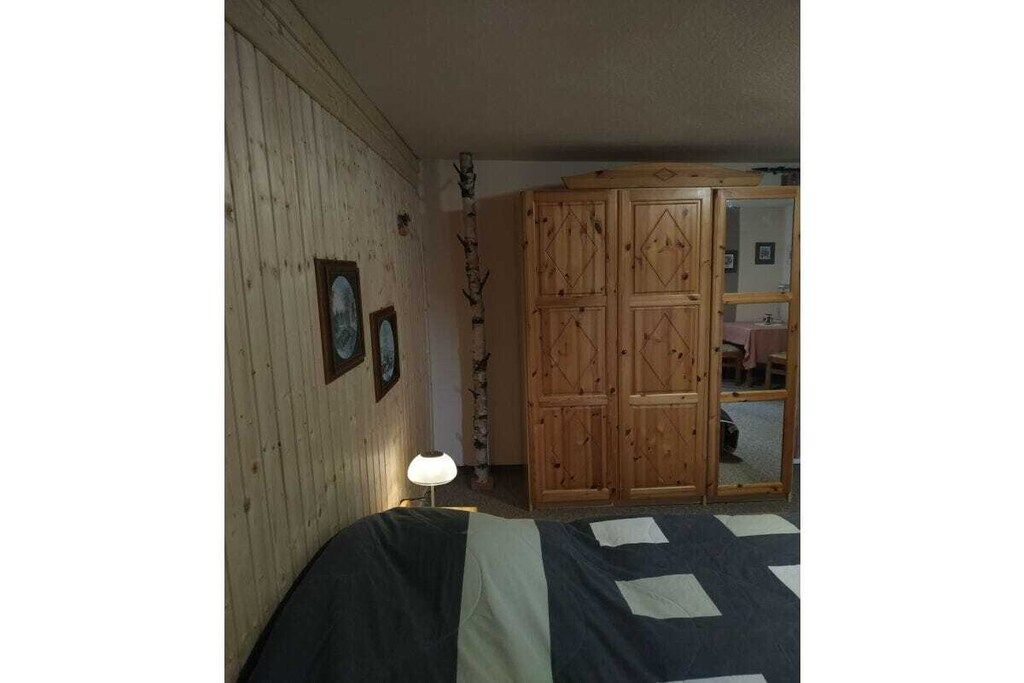 A room with a bed, wooden wardrobe, and a lamp.