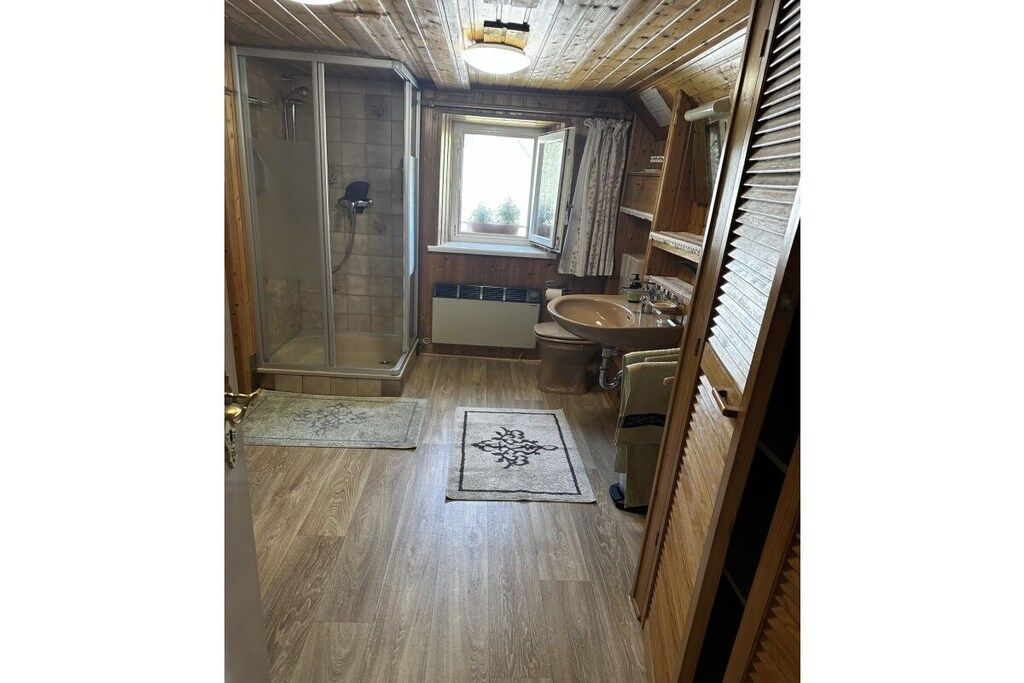 Un intérieur en bois avec une douche, un lavabo et une fenêtre.