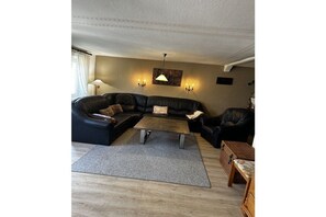 A living room with a sectional sofa, a coffee table, and a lamp. - Hex"nhäusla in Aufseß (Aufseß)