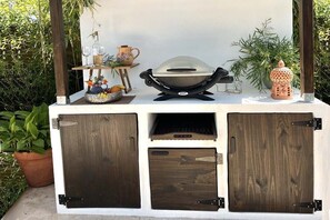 A wooden outdoor grill station with a built-in cabinet, a hanging wine glass holder, and decorative items. - Holiday home in Frejus with swimming pool (Frejus)