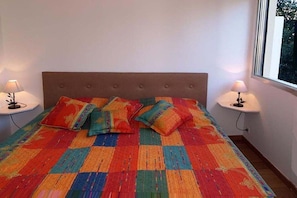 Un lit avec une couverture colorée et deux lampes de chevet.