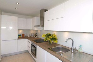 A modern kitchen with white cabinets, a stainless steel sink, and a built-in oven. - Holiday apartment with 1 bedroom (Antibes)