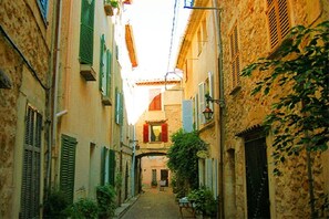 A narrow street with buildings on either side, a visible archway, and a small table with items on it. - Holiday apartment with 1 bedroom (Antibes)