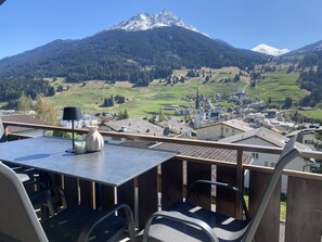Una terraza con mesa, sillas y vistas a una montaña y un pueblo.