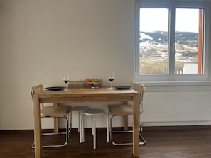 A dining table with four chairs, a bowl of fruit, and two wine glasses. - Satin Home Appartement/Fewo, Bad, WC Studio - 3 Betten by Interhome (Savognin)