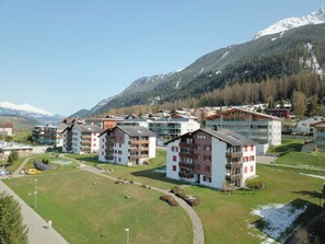 A residential area with multi-story buildings, a clear sky, and a mountain in the background. - Satin Home Appartement/Fewo, Bad, WC Studio - 3 Betten by Interhome (Savognin)
