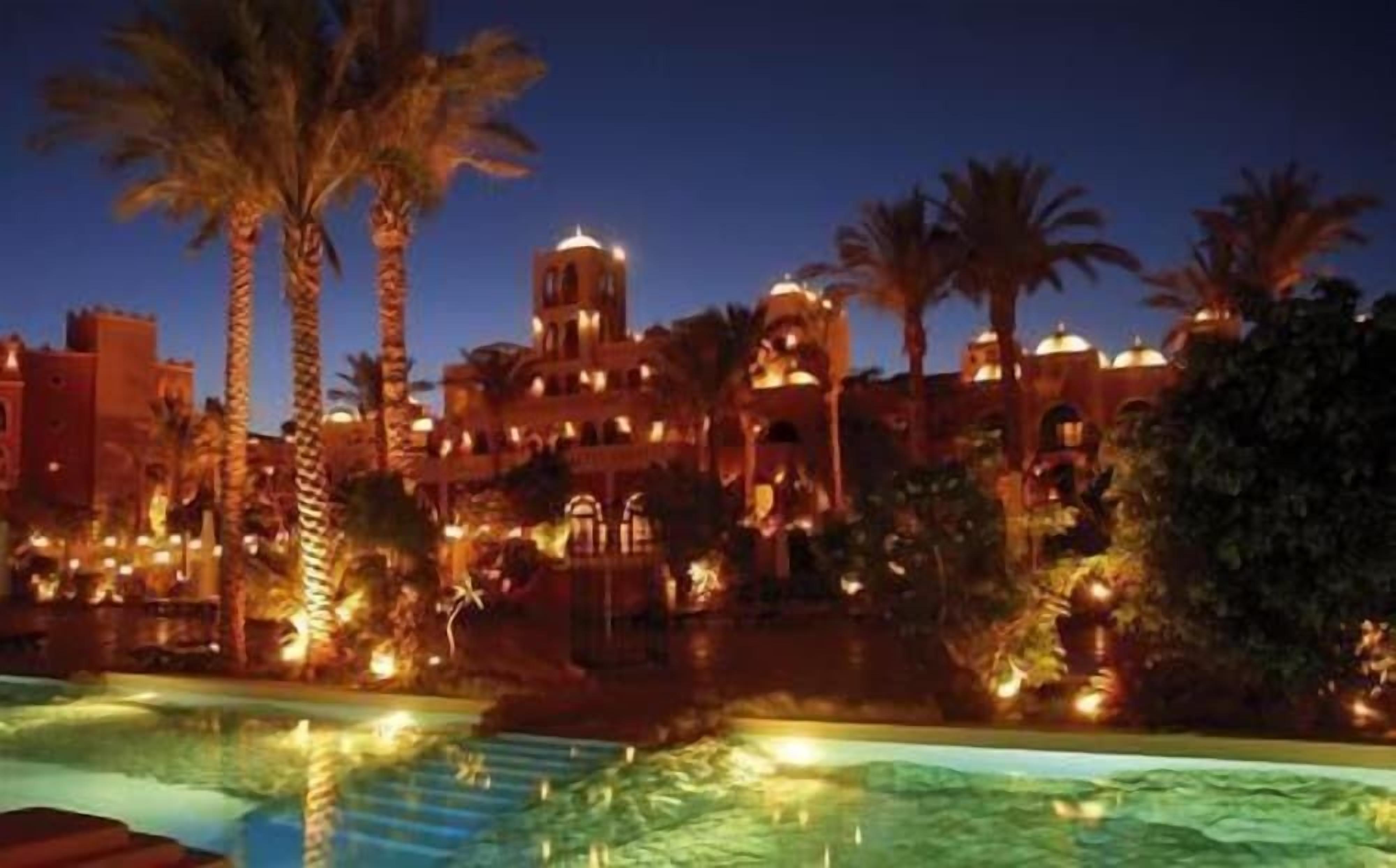 A hotel with a pool, palm trees, and a building with domed structures.