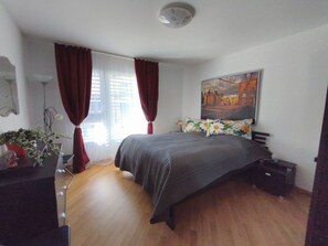 Ein Schlafzimmer mit einem Bett, einem Bild, einem Schreibtisch und einer Topfpflanze.